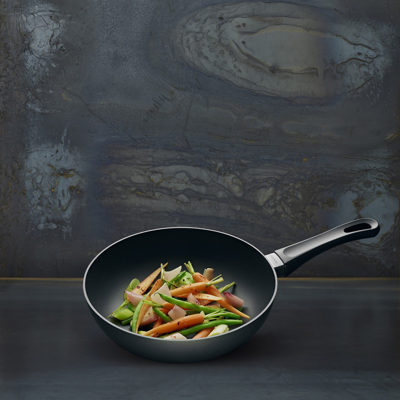Black frying pan with vegetables on a dark textured background